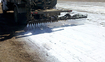 Dust suppression spray bar treating a logistics yard road